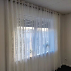 Fenster mit transparenter Gardine und dekorativem Seitenschal von M-Gardindendesign.