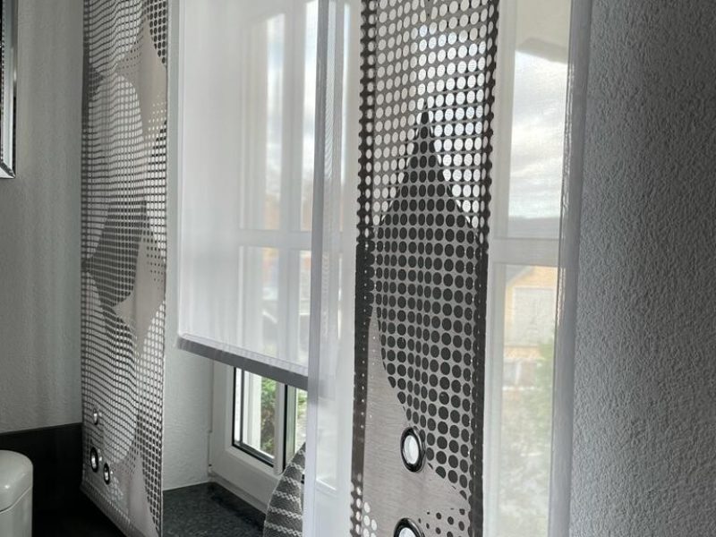 Wohnzimmer mit dekorativer Muster-Gardine von M-Gardinendesign in Paderborn.
