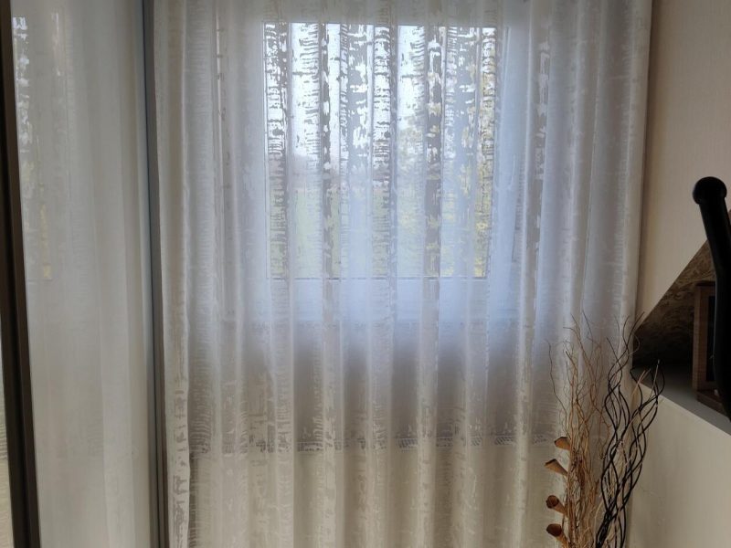 Fenster mit gemusterten, transparenten Gardinen von M-Gardindendesign.