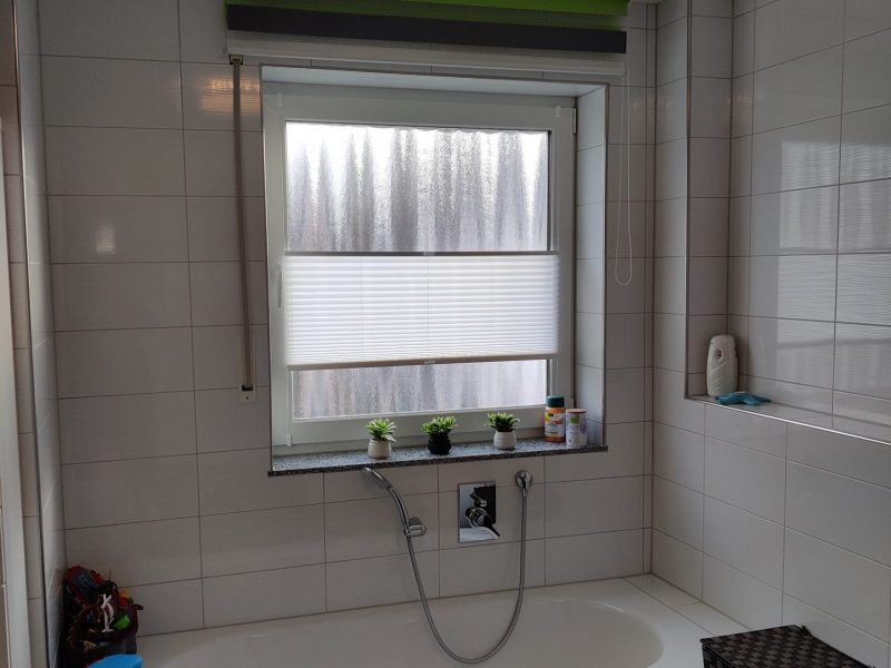 Badezimmerfenster mit maßgefertigtem Sichtschutzrollo von M-Gardindendesign.