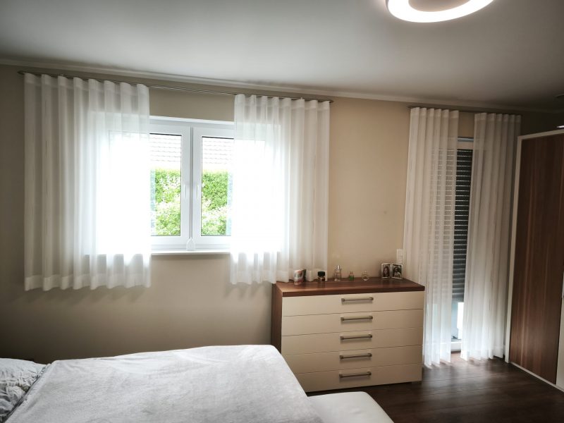 Schlafzimmer mit transparenten Vorhängen und maßgeschneiderter Fensterdekoration von M-Gardindendesign.