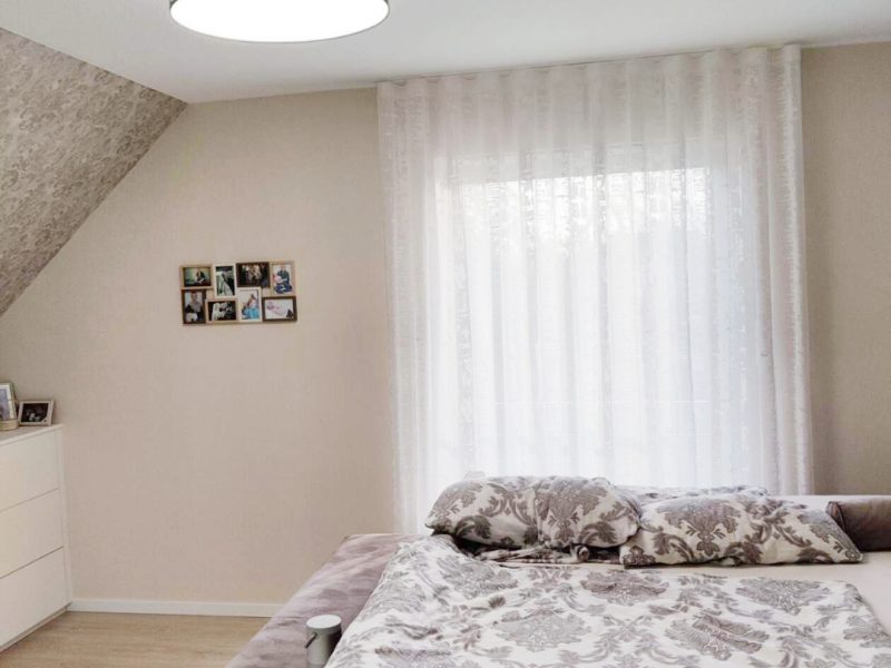 Schlafzimmer mit weißen, bodentiefen Vorhängen nach Maß von M-Gardindendesign.