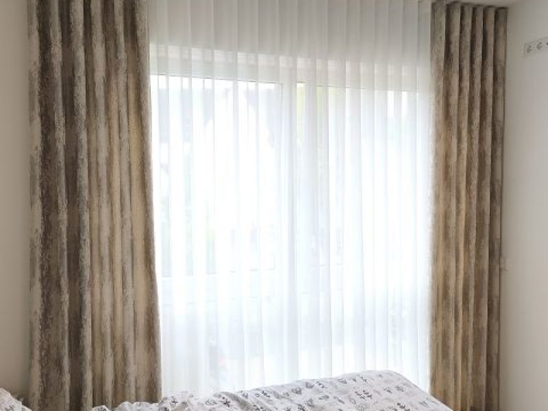 Schlafzimmer mit beigen, bodentiefen Vorhängen nach Maß von M-Gardindendesign.