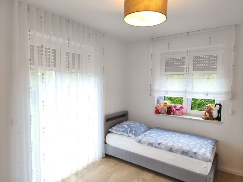 Schlafzimmer mit maßgefertigten Gardinen und dekorativen Seitenschals von M-Gardindendesign.