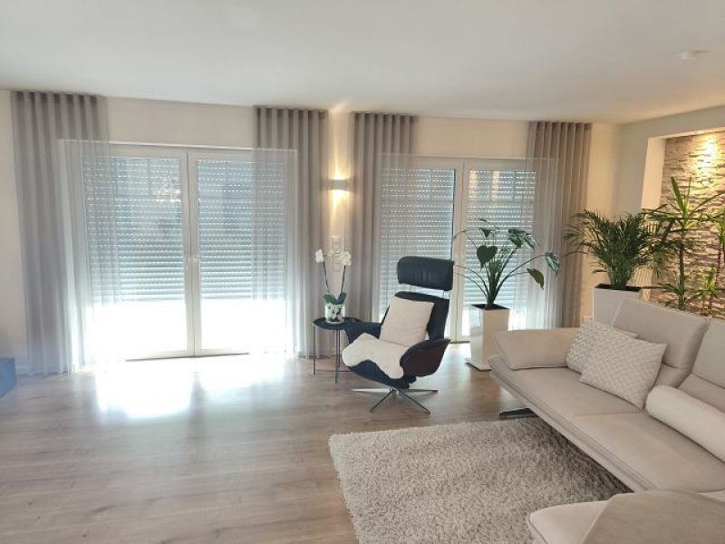 Helles Wohnzimmer mit maßgefertigten Gardinen und Sichtschutz von M-Gardindendesign in Paderborn.