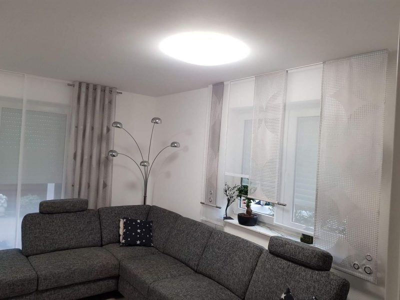 Helles Wohnzimmer mit maßgefertigten Gardinen und Vorhängen als Sichtschutz von M-Gardinendesign.
