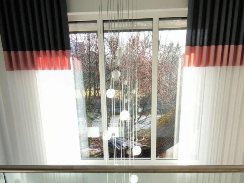 Wohnzimmerfenster mit maßgefertigten Vorhängen und farbigen Akzenten von M-Gardindendesign in Paderborn.
